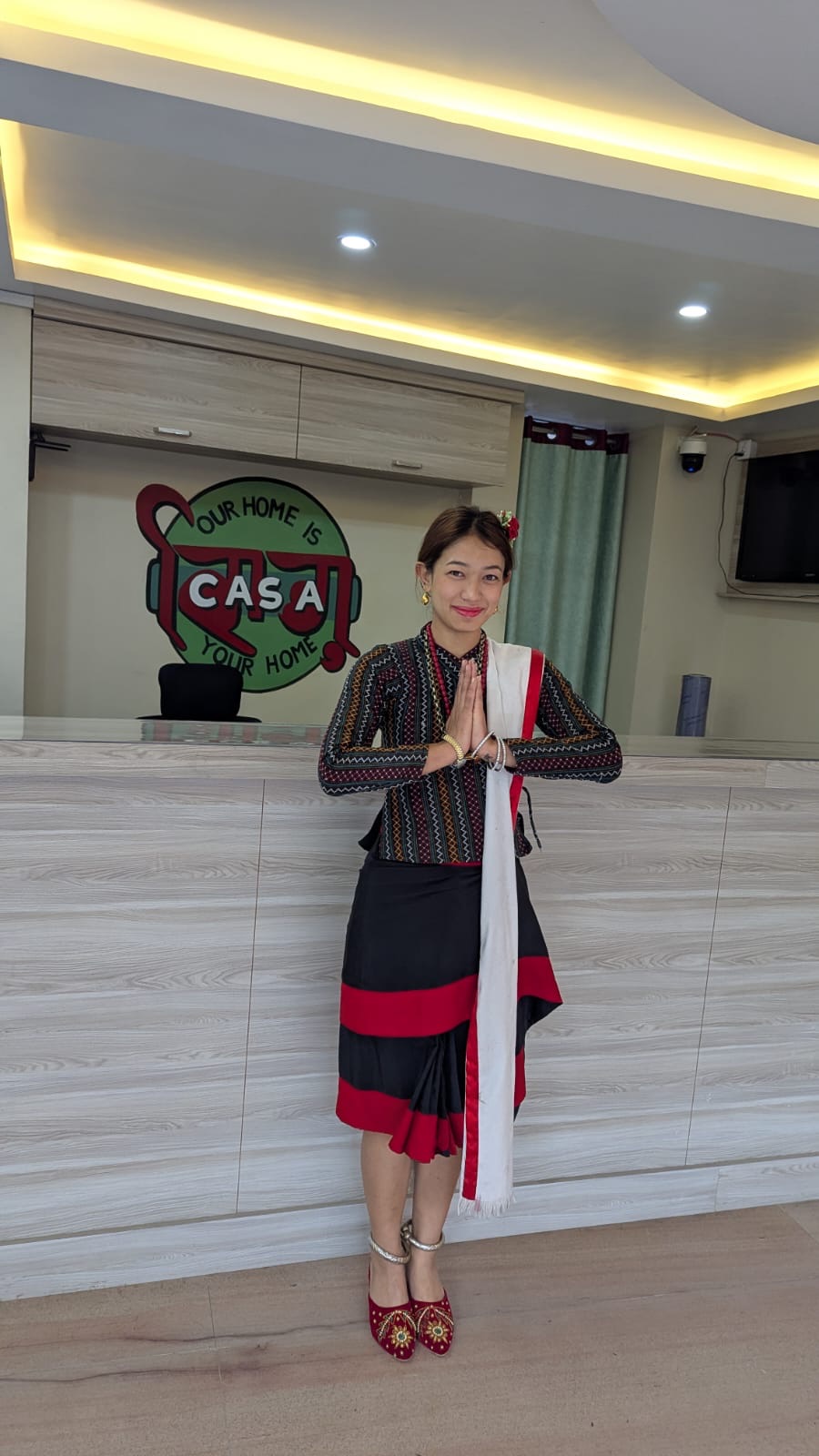 A host in traditional Newari dress offers namaste at the Jhigu Casa reception.